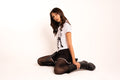 A woman kneeling on a white studio floor wearing a white graphic t-shirt, black skirt, black polka-dot and silver trim shorts, black tights, and black lace-up boots. punk graphic polo | LA Apparel polo | pink polo shirt | pique polo shirt | Y2K punk shirt | grunge girl graphic tee | alt fashion polo | edgy preppy top | platform boots outfit | pleated mini skirt outfit | Y2K alt fashion #altgirl #y2kpunk #gorpcore #polowithattitude #graphicpolo